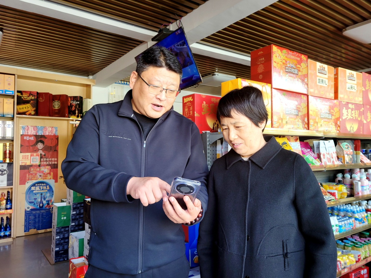 客戶經理劉敬國(左一)幫助吉祥超市建立“鄰裡生活福利群”