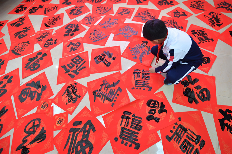 2026年1月29日，在山東省青島市市北區重慶路第三小學舉辦的“萬福迎春”書法活動上，一名學生在擺放福字。
