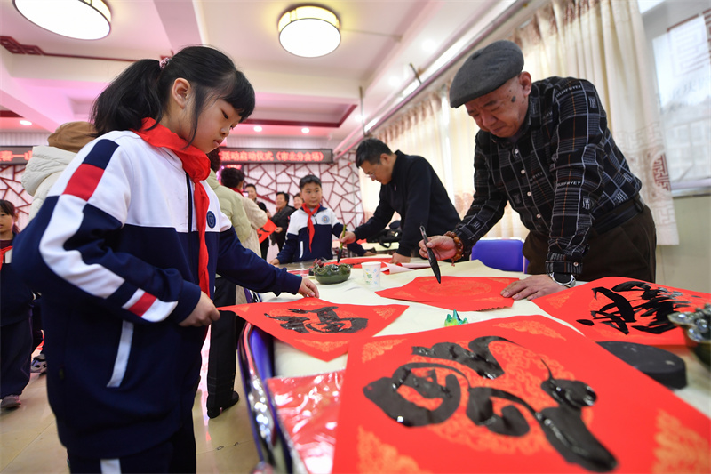 2026年1月29日，在山東省青島市市北區重慶路第三小學舉辦的“萬福迎春”書法活動上，學生在觀賞書法家書寫的福字。