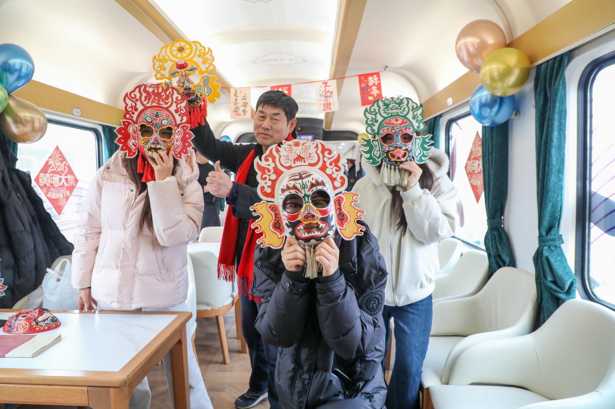 1月29日，在“齊魯1號·黃河大集”主題車廂，乘客與侯氏社火臉譜代表性傳承人侯志新（后排中）共同體驗傳統藝術魅力。劉洋攝