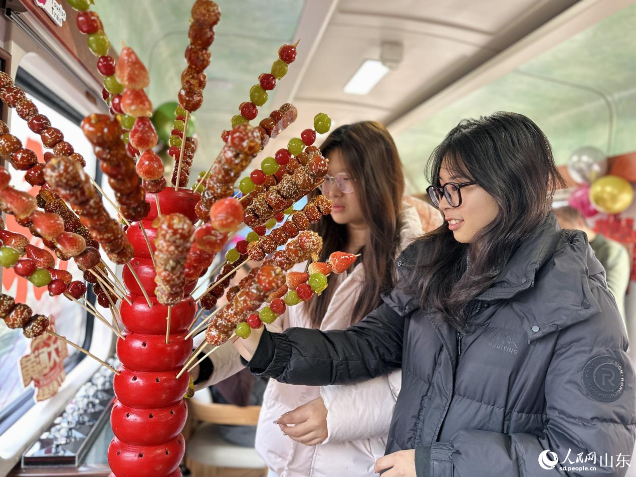 1月29日，在“齊魯1號·黃河大集”主題車廂，乘客選購糖葫蘆。人民網記者 喬姝攝