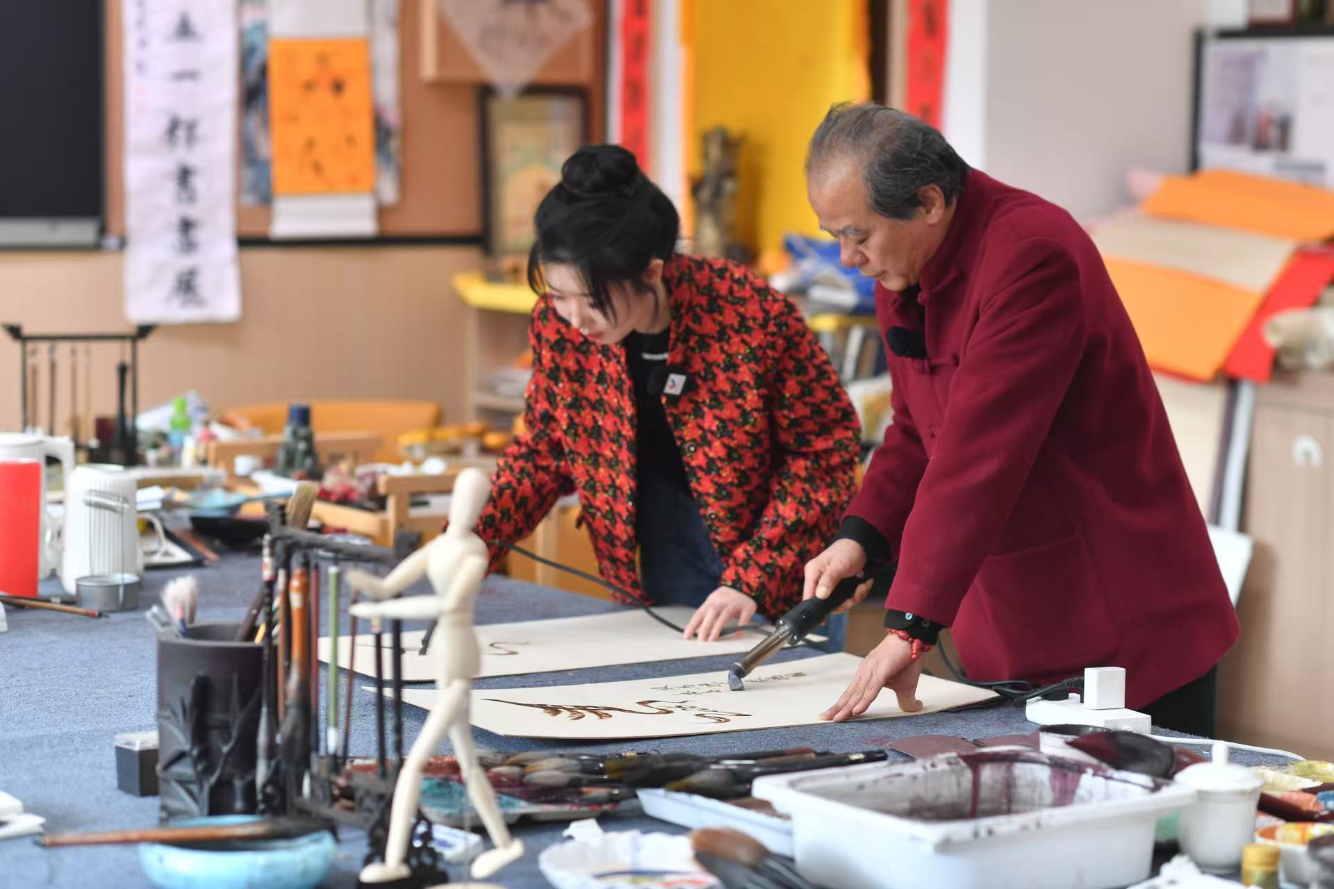 非遺烙畫傳承人闞志經和學生在創作馬年烙畫