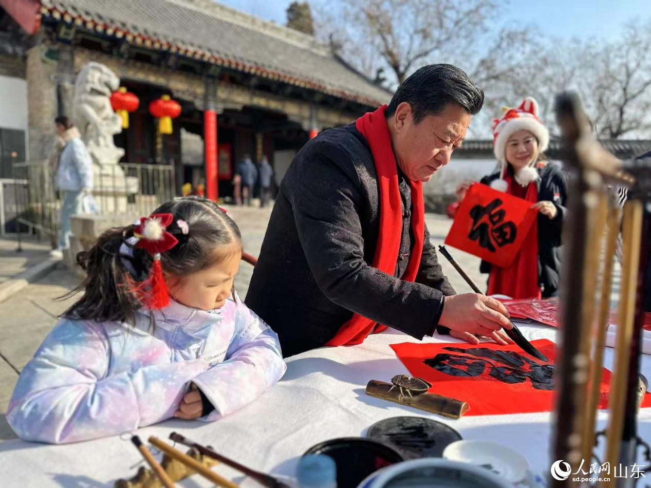 孔子书画院名誉院长孔祥胜挥毫泼墨，现场书写春联福字。人民网记者 乔姝摄