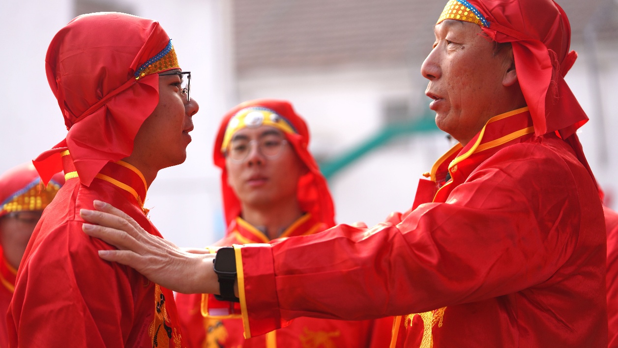 老藝人幫李洪熠（左一）整理舞龍燈的衣服。董乃德攝