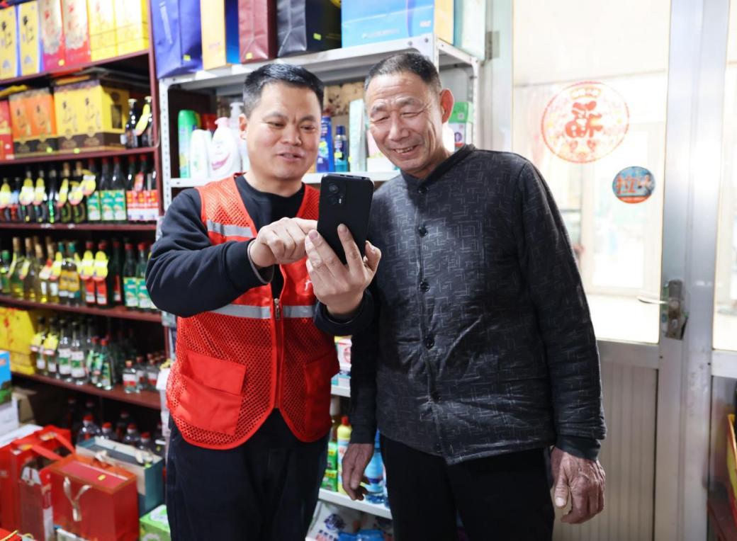 客户经理徐宝平(左)向惠惠超市店主李广文演示订货系统