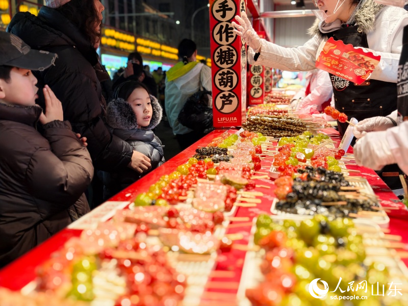 小朋友在山東省青島市市北區糖球會大鮑島美食街上選購特色糖球。人民網記者 劉穎婕攝