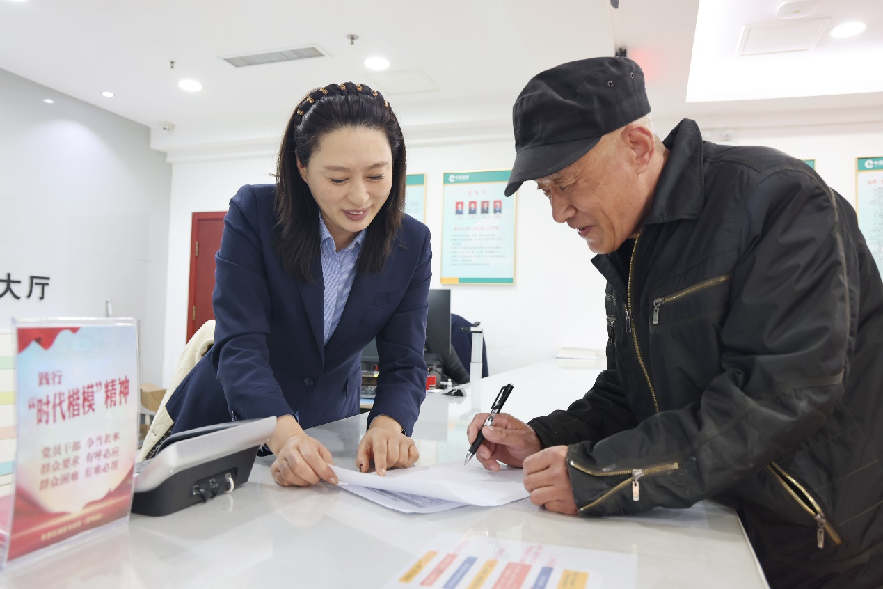 証件管理員宋桂香正在幫助張大爺辦理許可証延續業務