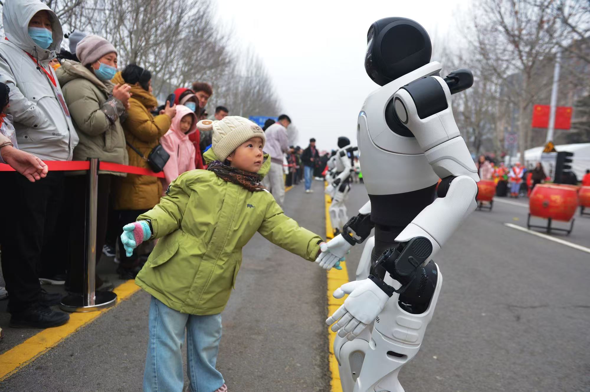 一名小朋友与河套街道展示的武术机器人互动
