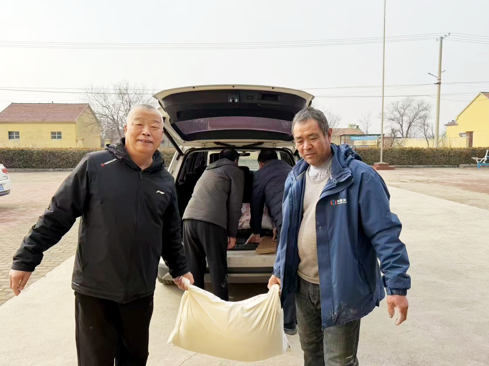 駐村幫扶干部袁敬海（左）和韓屋村村民為困難零售戶送生活物資