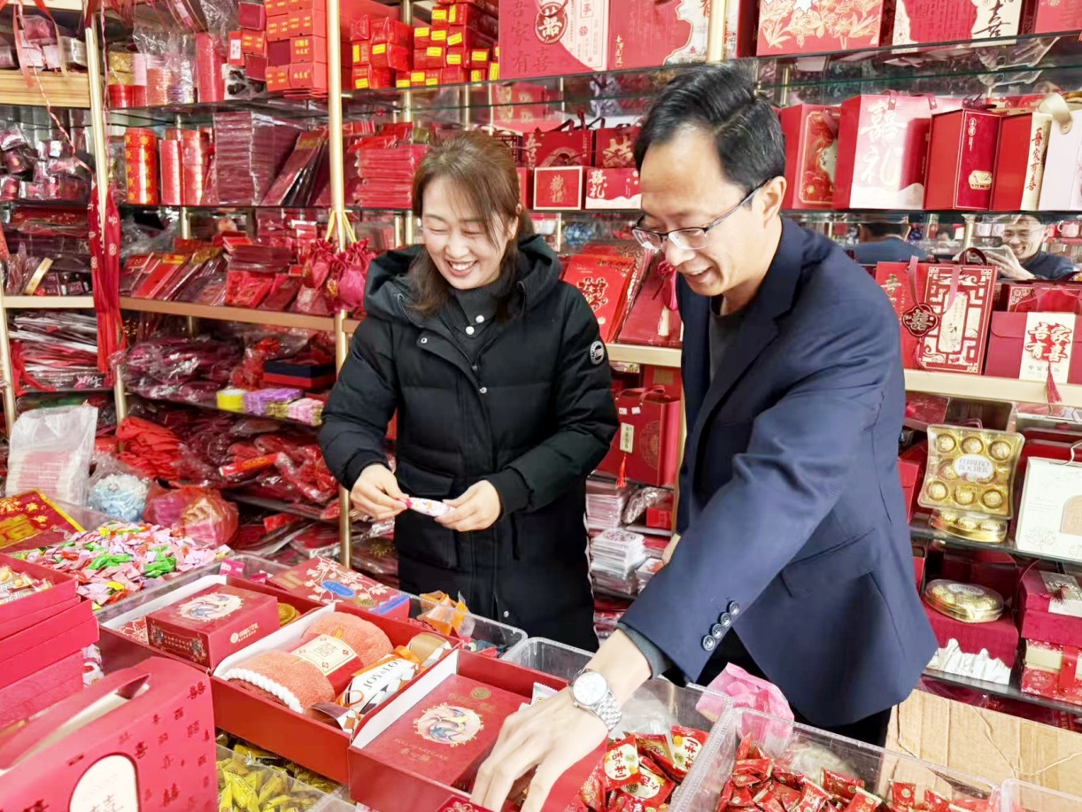 客户经理盖海峰(右一)指导恒达烟酒商行店主董婷调整店内布局