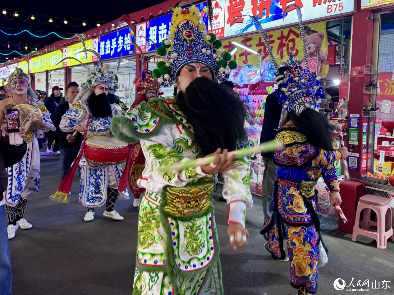 舞者臉繪臉譜、身著彩衣,步伐鏗鏘。人民網 鄭昕橋攝