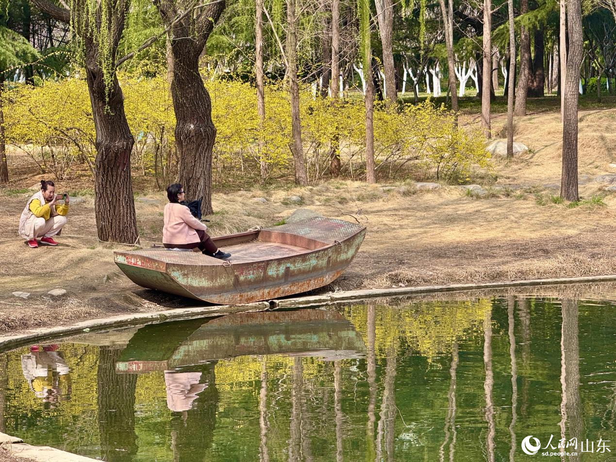 游人在岸边拍照,定格春日美景。人民网 郑昕桥摄