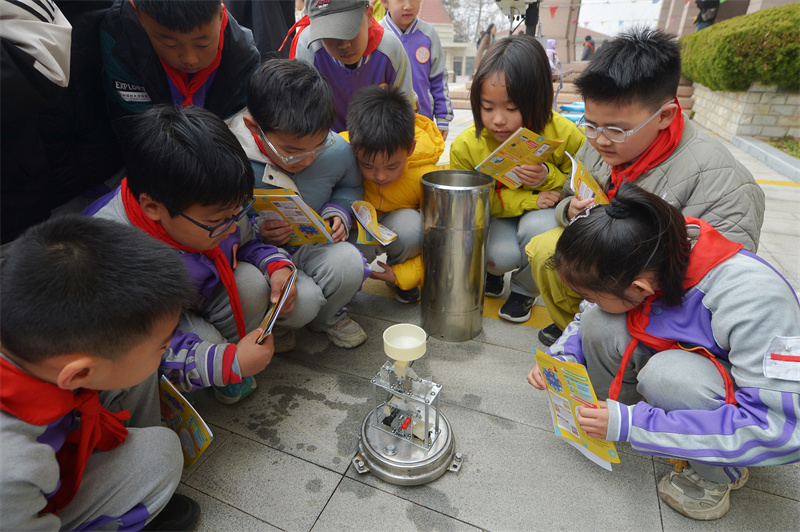 2026年3月21日,在山东省青岛市市北区普新小学开展的气象科普主题研学活动上,学生们参观测量降水量的数字化仪器。王海滨摄