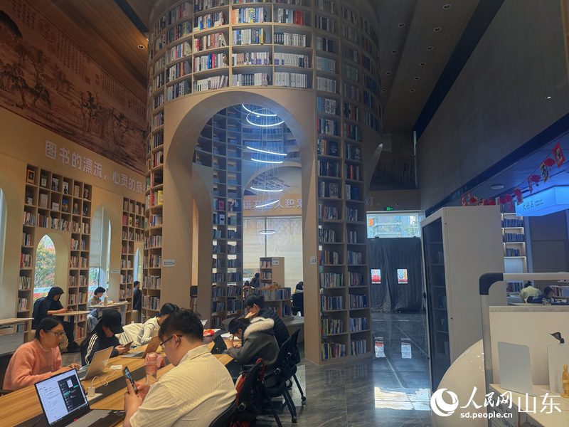 圆柱形书塔下，读者翻阅资料专心学习、办公。人民网 邢曼华摄