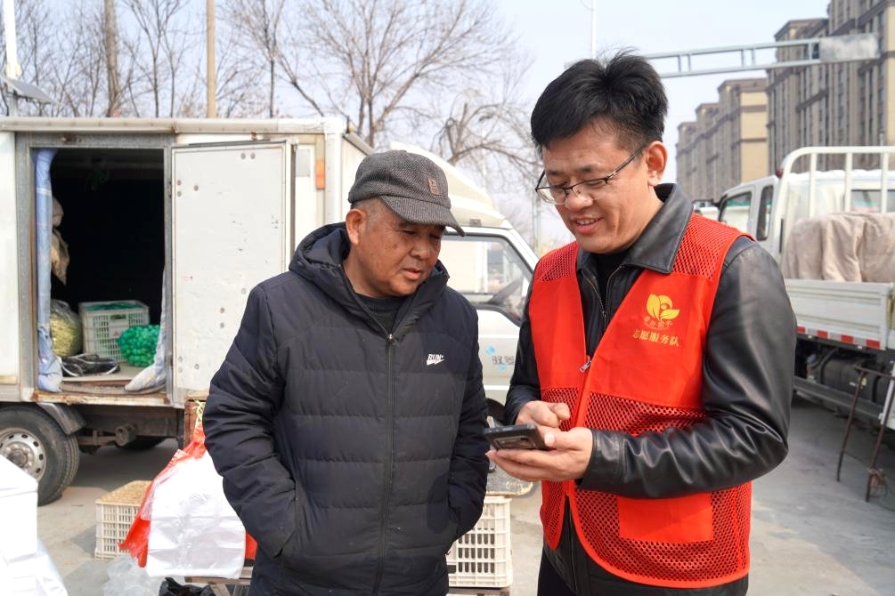 志願者在集貿市場講解反詐典型案例