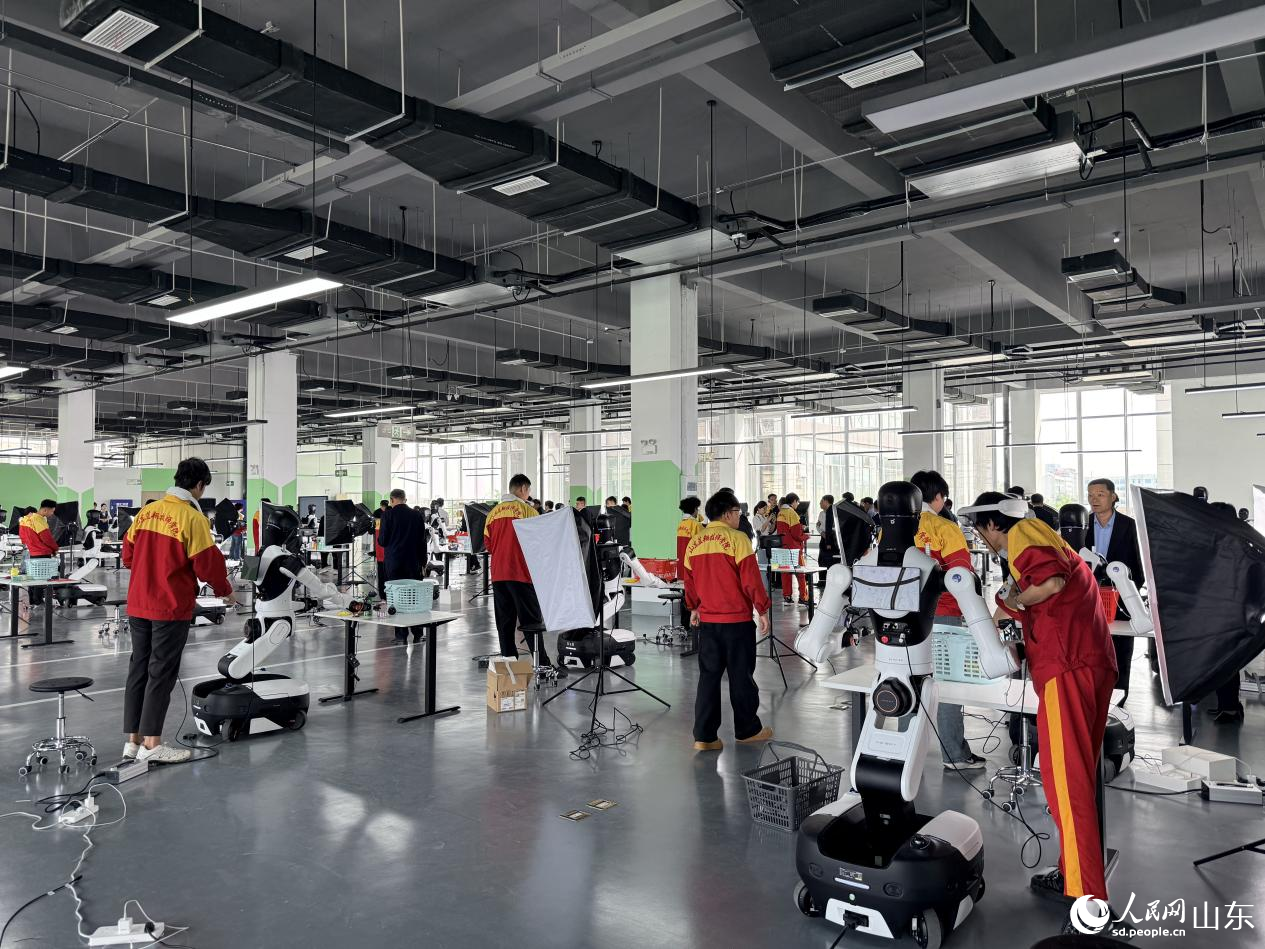 二楼数采中心内，工作人员操作 G1、G2 轮式机器人进行分拣作业。 人民网 李子悦摄