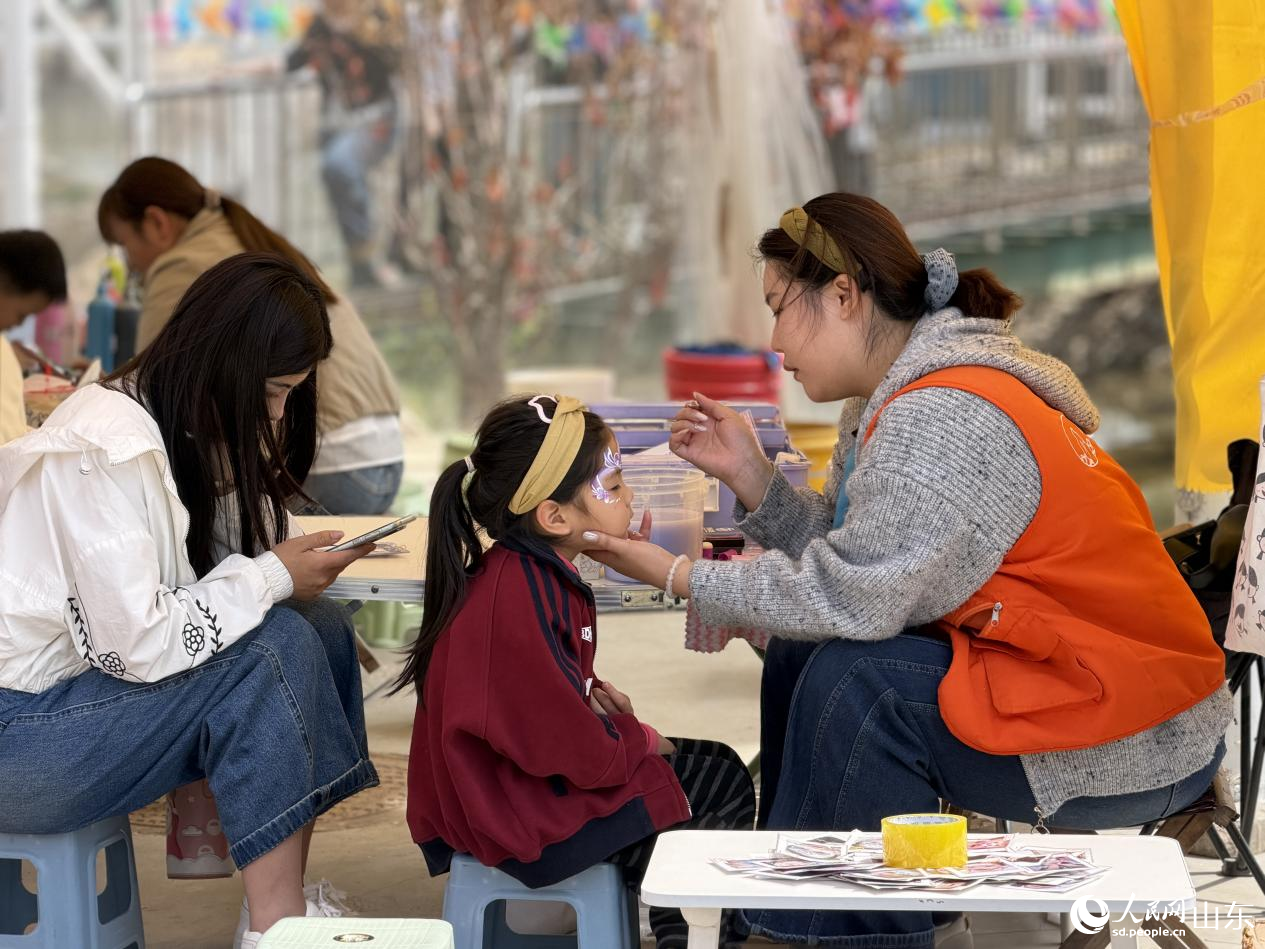 姜会芳的摊位前，彩绘师正专注地给孩子画着面部彩绘。人民网记者 乔姝摄