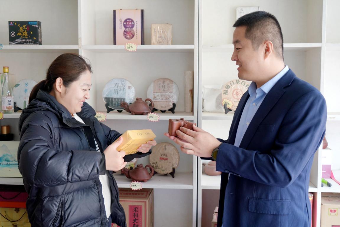店主陳思(左)與客戶經理張貝貝(右)討論茶品陳列