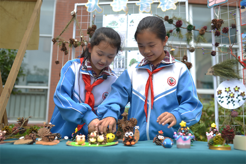 2026年5月21日，在山東省青島市舉辦的“紅領巾愛自然”生物多樣性科普教育活動上，華陰小學的學生在擺放創意鬆塔。