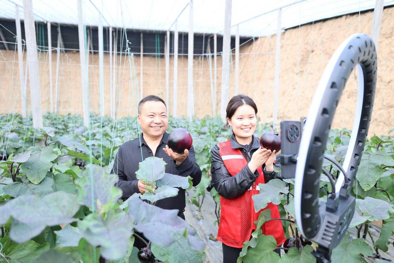 志愿者魏欣然(右)与农户在田间开展直播助农活动