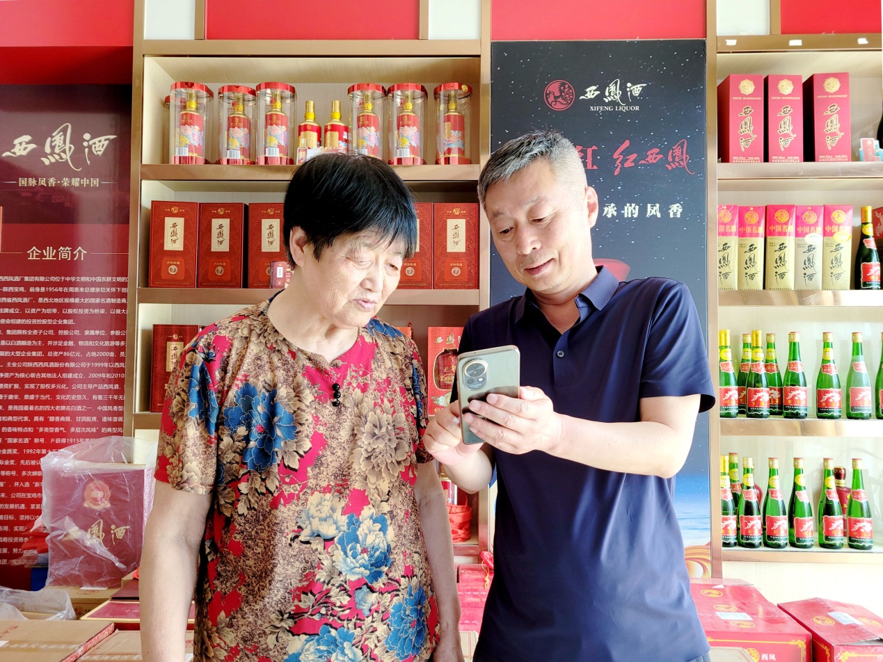 市场经理马相峰（右一）指导张金美查看店铺盈利情况