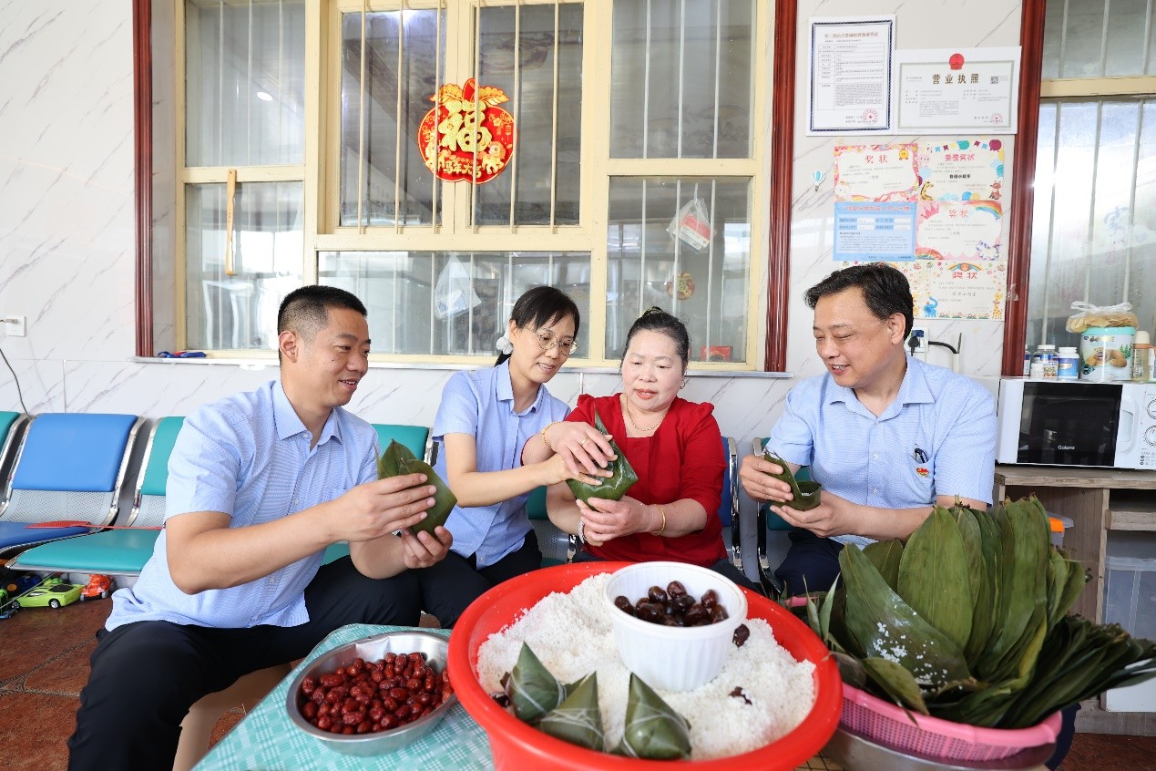 基层工作人员与零售户简仁先一起包粽子