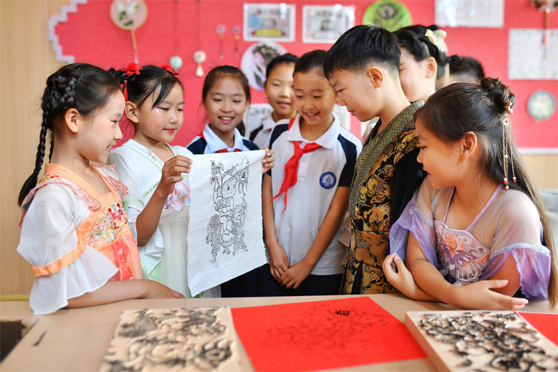 2026年6月17日，在山东省青岛市城阳区白云山学校开展的“传统文化润童心”主题活动上，学生们在观赏印制的木版年画。王海滨摄