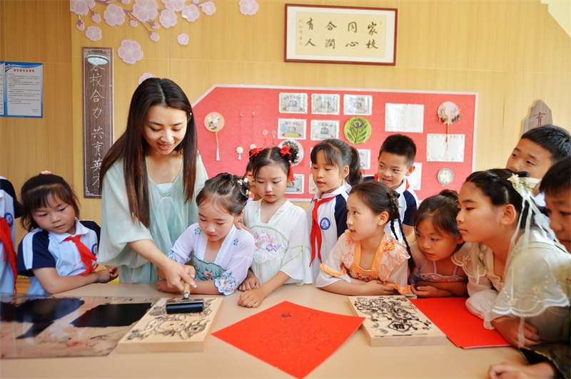 2026年6月17日，在山东省青岛市城阳区白云山学校开展的“传统文化润童心”主题活动上，老师在指导学生学习木版年画制作。王海滨摄