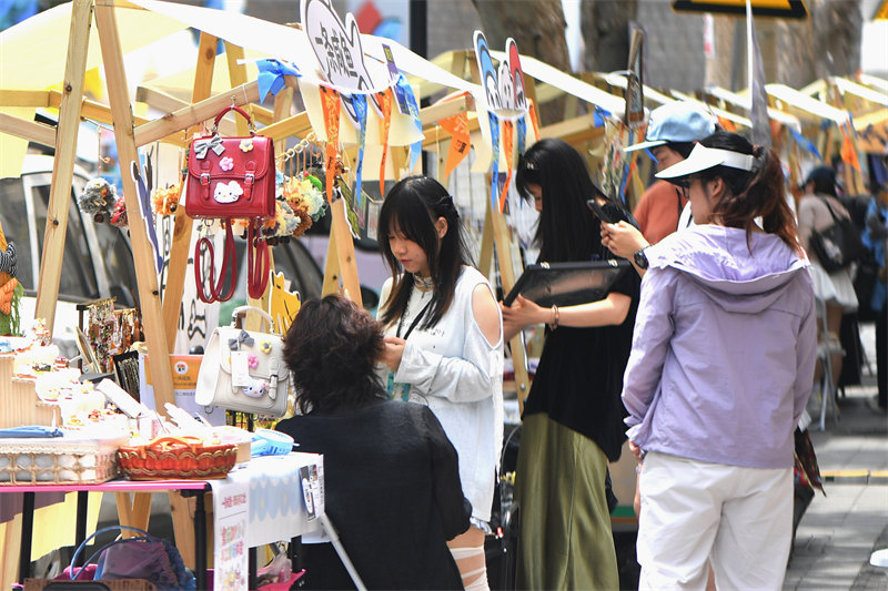 2026年6月26日，在山东省青岛市市北区无棣路“波螺油子·拾贰阶”历史街区，游客在艺术市集上游玩选购。王海滨摄