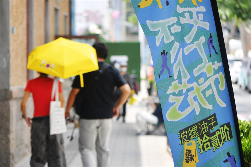 2026年6月26日，在山东省青岛市市北区无棣路“波螺油子·拾贰阶”历史街区，游客在“不平行艺术节”上打卡游玩。王海滨摄