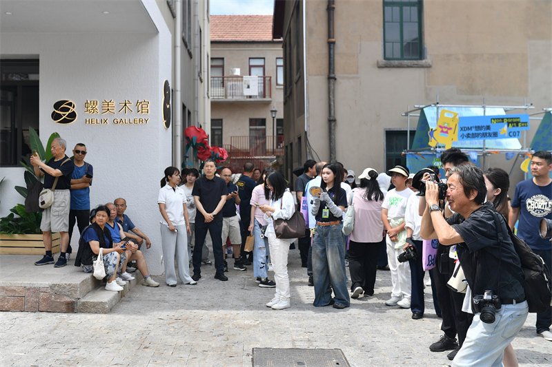 2026年6月26日，在山东省青岛市市北区无棣路“波螺油子·拾贰阶”历史街区，游客在“不平行艺术节”上打卡游玩。王海滨摄