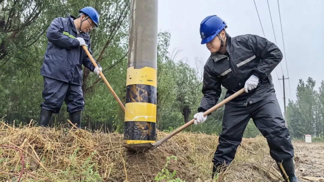 国网滨州供电公司工作人员冒雨对10千伏城西二线69号杆基础进行培土加固。代福永摄
