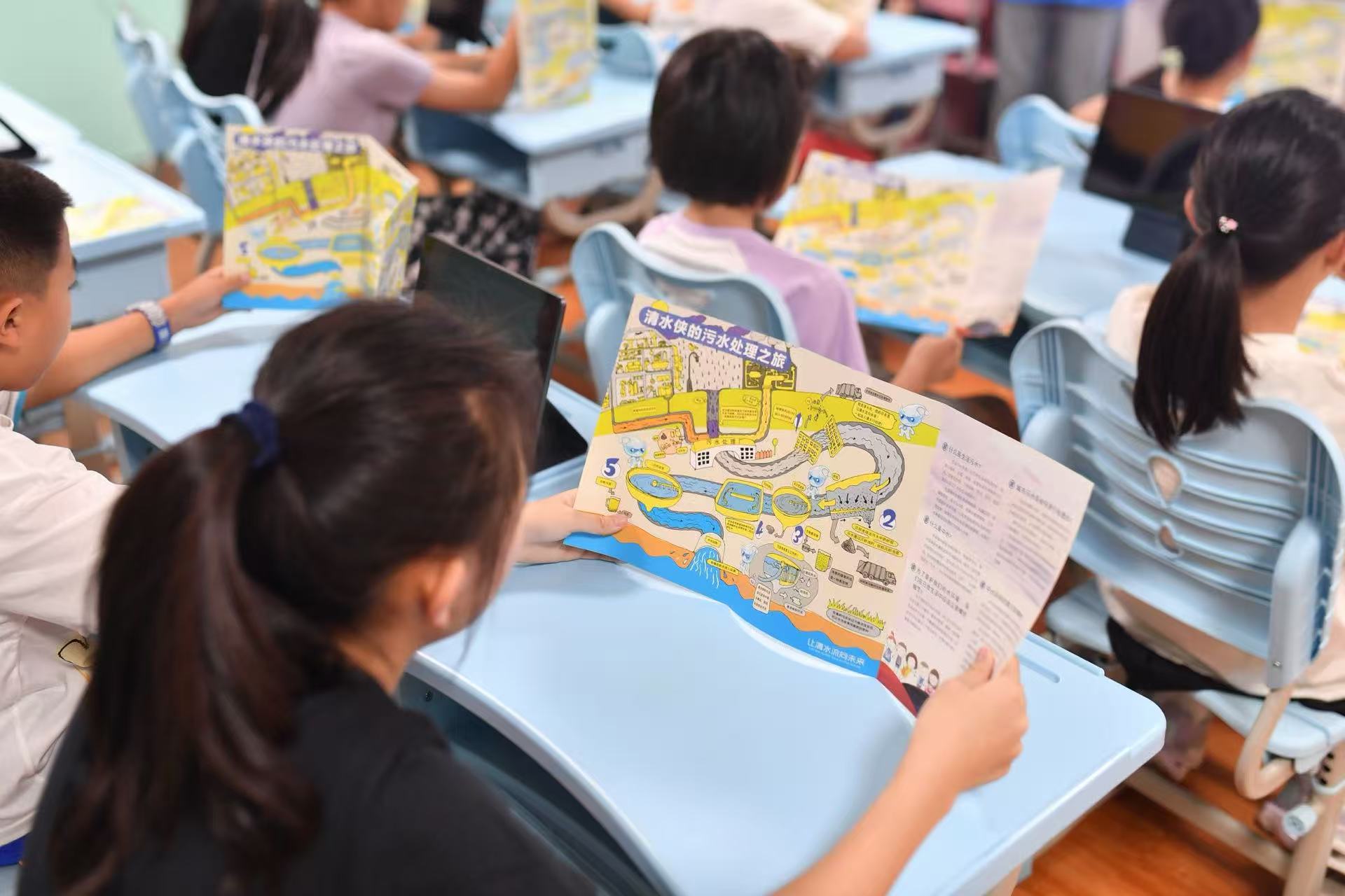 8月12日，在山東省青島市海泊河再生水廠，學生們在AI+“清水小課堂”上觀看“清水俠的污水處理之旅”宣傳冊。
