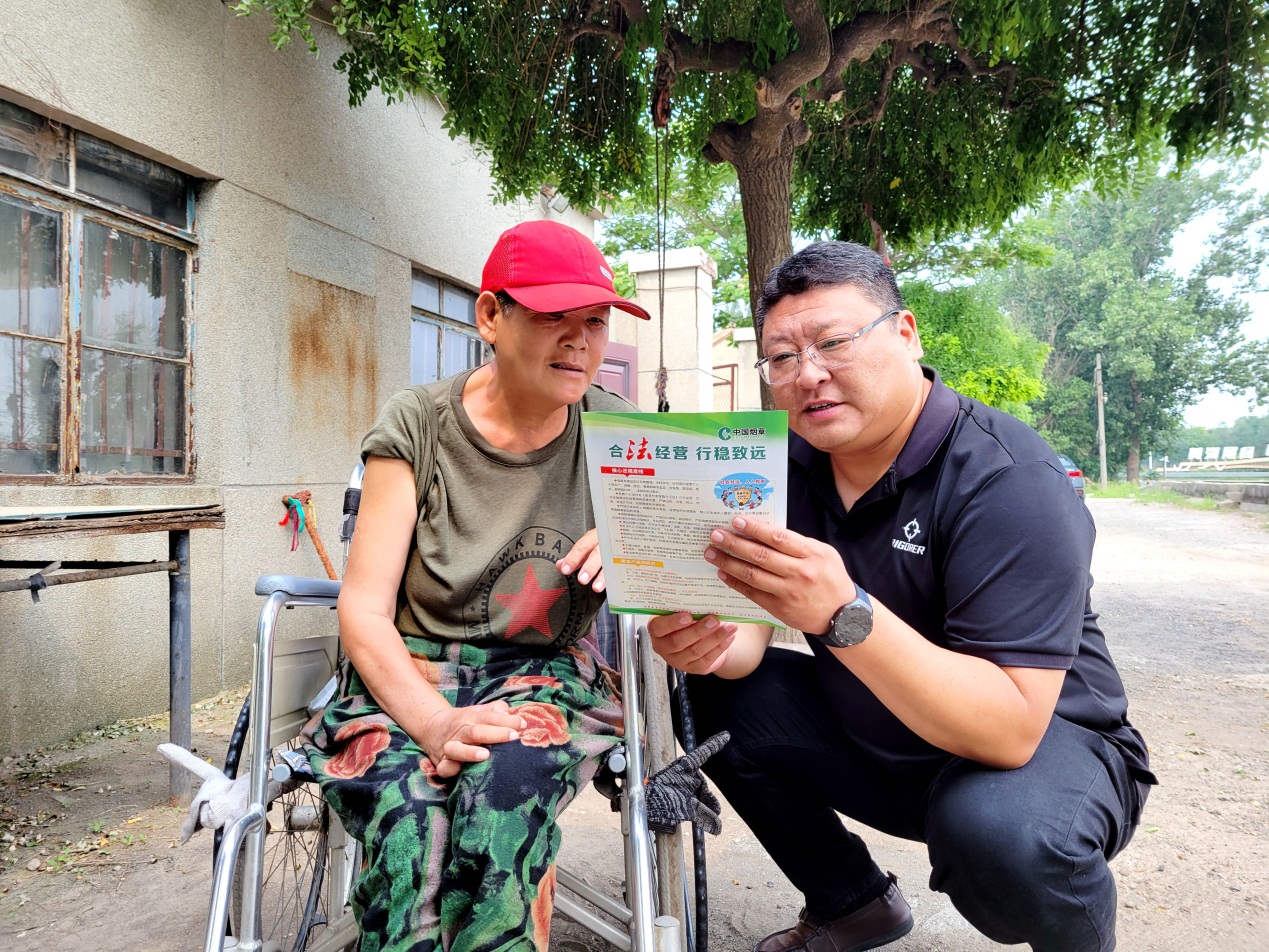 志願者劉敬國（右一）向零售戶講解煙草相關法律法規政策