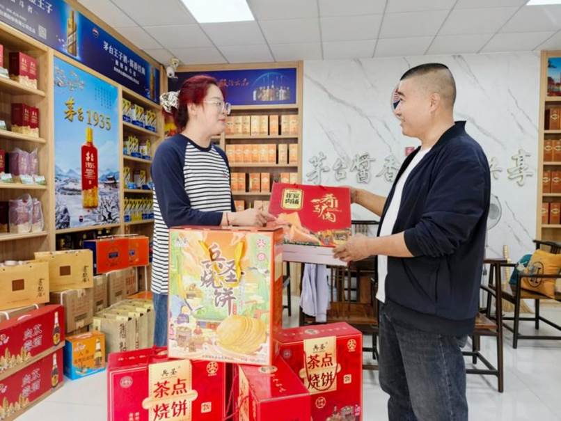 益中商行店主尹国林（右）向顾客推介本地特产
