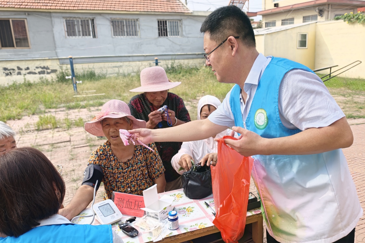 宣傳科負責人匡京華現場發放中醫健康宣傳資料和芳香化濁的中藥香囊。