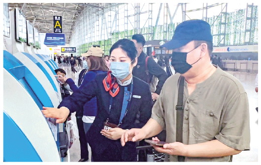 □記者常青通訊員王淑慧報道  4月28日，濟南機場，旅客在工作人員引導下取票。